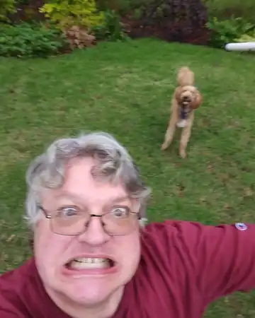Luke outdoors with his dog in the background